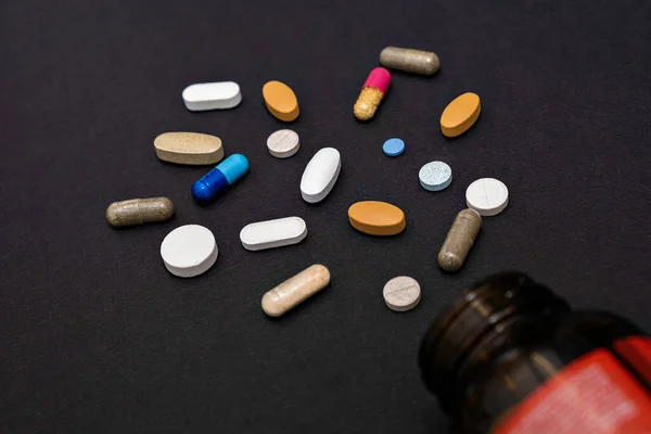 Крупним планом барвисті різноманітні порошкові м'які капсули таблетки вітаміни і баночки для пляшок на чорному тлі — стокове фото