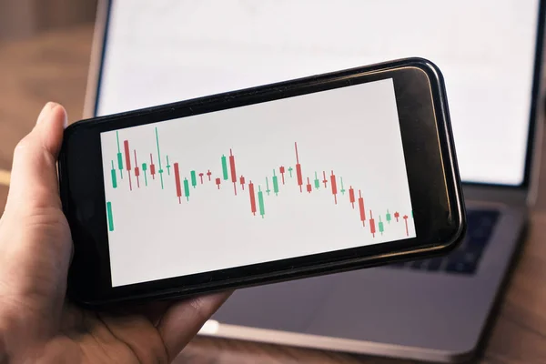 Close up n mano tenendo smart phone con grafico a candela per il commercio borsa investimento cripto valuta — Foto Stock