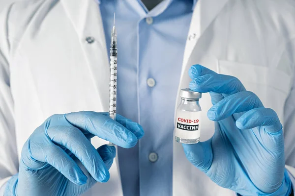 Концепція вакцинації від коронавірусу в руці лікаря скляної банки для ампули. Білий халат і рукавички — стокове фото