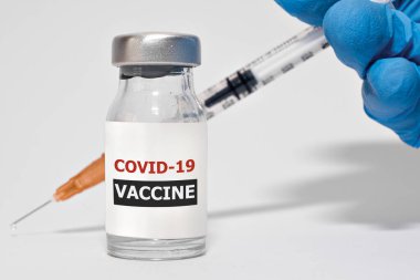 COVID-19 Coronavirus aşısı ve şırınga koruyucu eldivenlerle doktor elinde