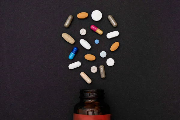 Крупним планом барвисті різноманітні порошкові м'які капсули таблетки вітаміни та пляшки для банок на чорному тлі — стокове фото