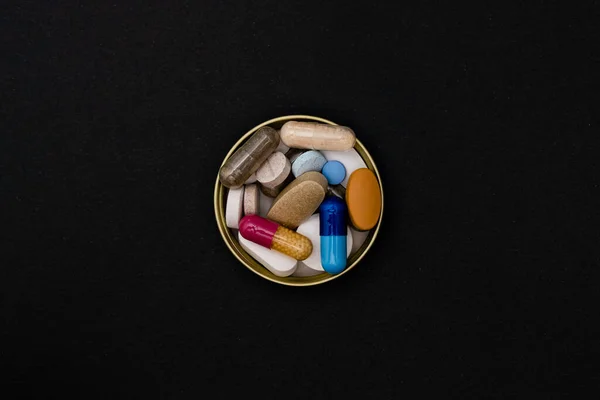 Närbild färgglada pulver mjuka kapslar piller vitamin blå rosa gul brun kosttillskott på svart bakgrund — Stockfoto