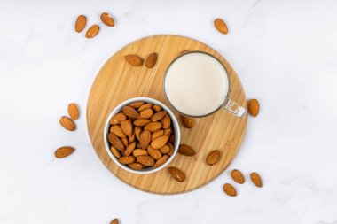 Badem sütü bardakta, badem ve ahşap bir masa.