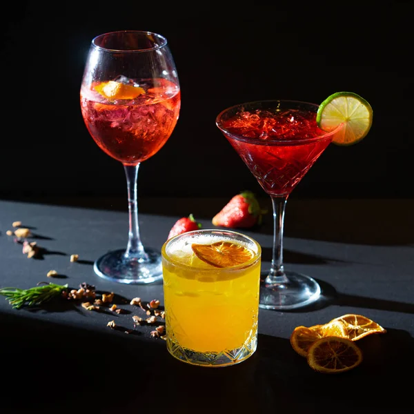 Aperol Spritz e coquetéis aperitivos vermelhos e amarelos em vidro com gelo sobre fundo preto — Fotografia de Stock