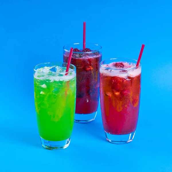 Coquetéis frescos vermelhos e verdes smoothie jusice em vidro com gelo sobre fundo azul. desintoxicação da bebida vitamínica — Fotografia de Stock