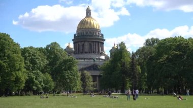 İnsanlar parkta çimlerde dinleniyor, St. Isasakievsky Katedrali manzarası, yaz günü. Rusya, Saint Petersburg Haziran 2021