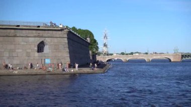İnsanlar Neva Nehri 'ndeki Peter ve Paul Kalesi' nin duvarlarında güneşleniyorlar. Rusya, Saint Petersburg Haziran 2021