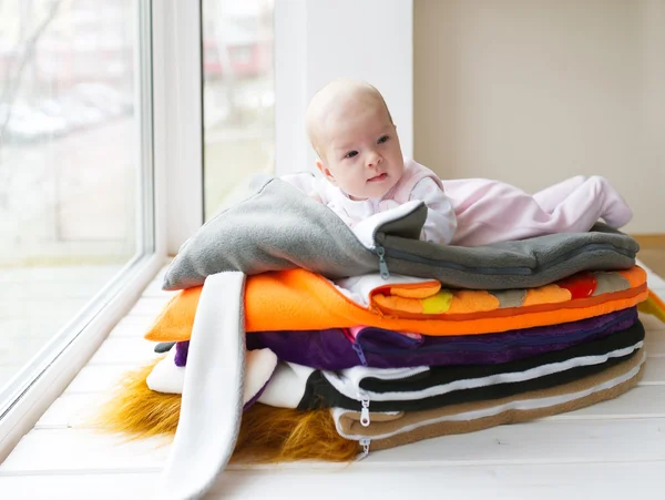 De baby ligt op handdoeken op een venster. — Stockfoto