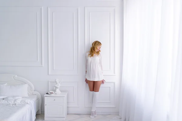 La chica posa en un magnífico dormitorio blanco . — Foto de Stock