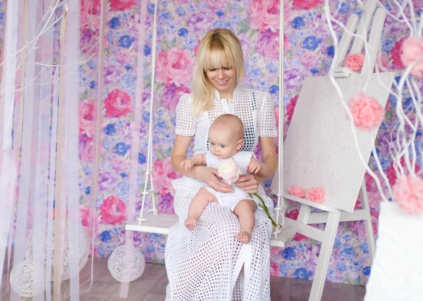 Anne ile küçük kızı sallamak kreş salıncak üzerinde.