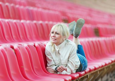 Kız bir bankta yatıyor. Spor Stadyumu.