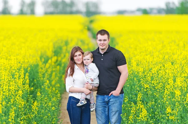 De vader, moeder en dochter onder bloeiende koolzaad. — Stockfoto