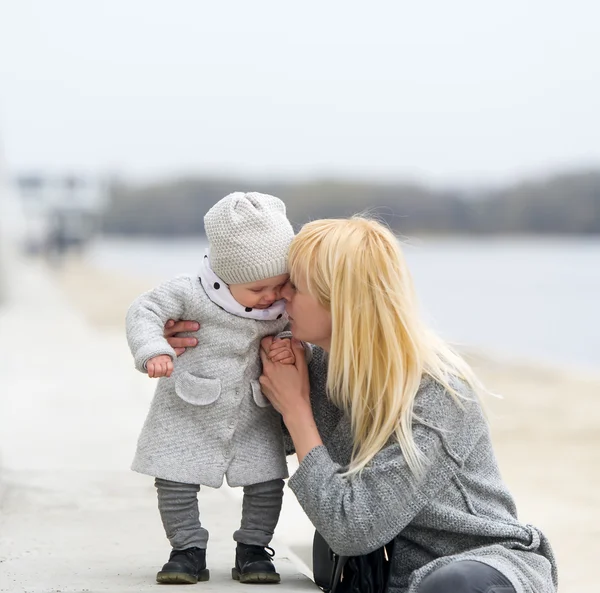 Mother gently embraces and kisses the little daughter. — Stock Photo, Image