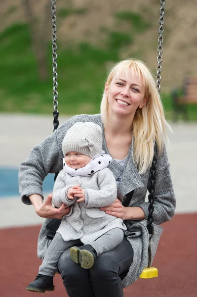 Madre con la pequeña hija sacudida en un columpio . —  Fotos de Stock