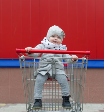 Küçük kız alışveriş sepetindeki oturur.