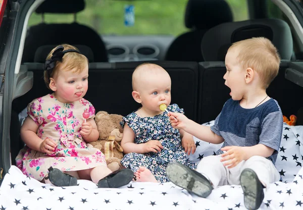 Tre bambini siedono nel portabagagli dell'auto . — Foto Stock