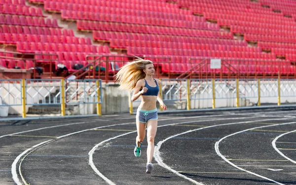 The sportswoman runs on a path at stadium. — Stock Photo, Image