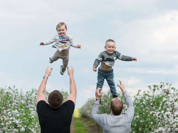 Dois pais jogam as crianças para cima . — Fotografia de Stock