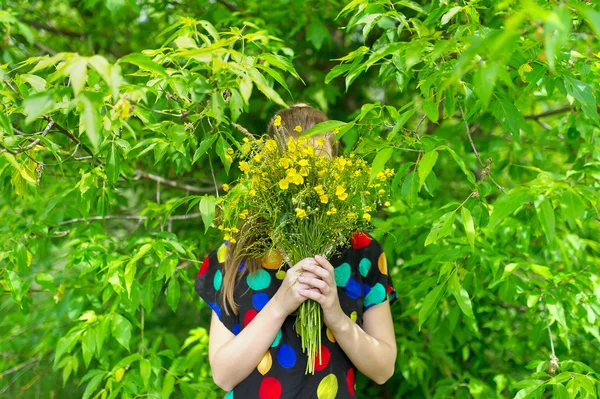 Dziewczyna obejmuje twarz z bukietem kwiatów żółty. — Zdjęcie stockowe