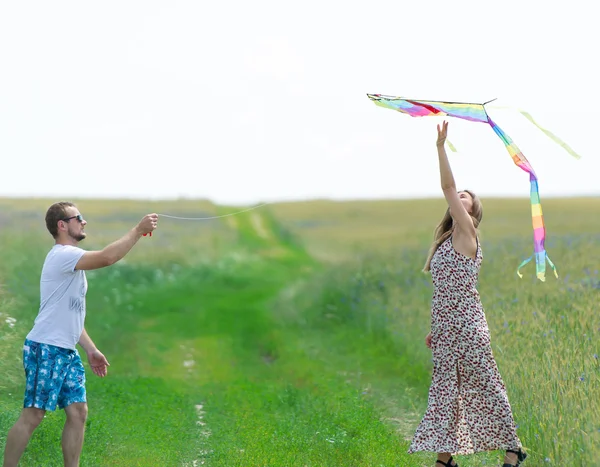 Couple aimant jettent cerf-volant sur une prairie — Photo