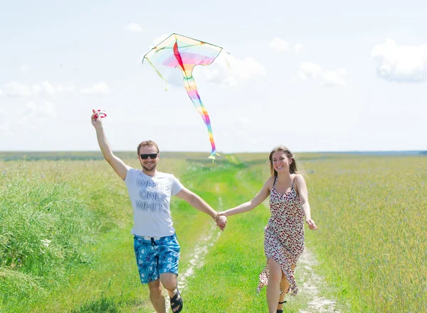 Älskande par är fling kite på en äng — Stockfoto