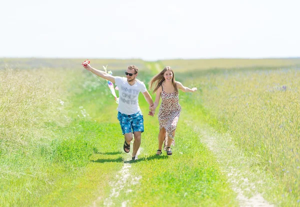 Älskande par är fling kite på en äng — Stockfoto