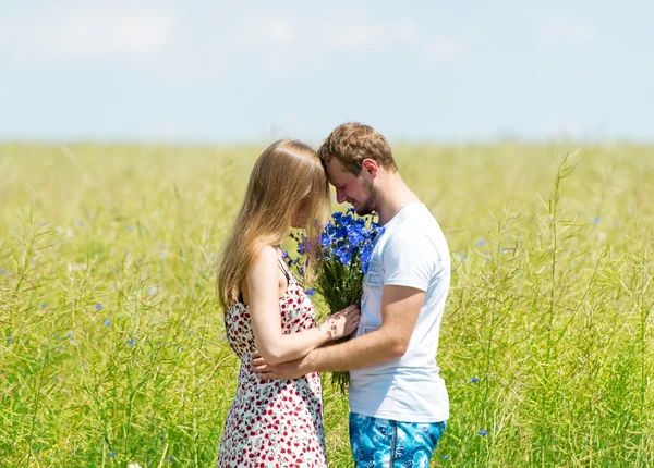 Beau couple avec bouquet de fleurs debout sur la prairie de printemps — Photo
