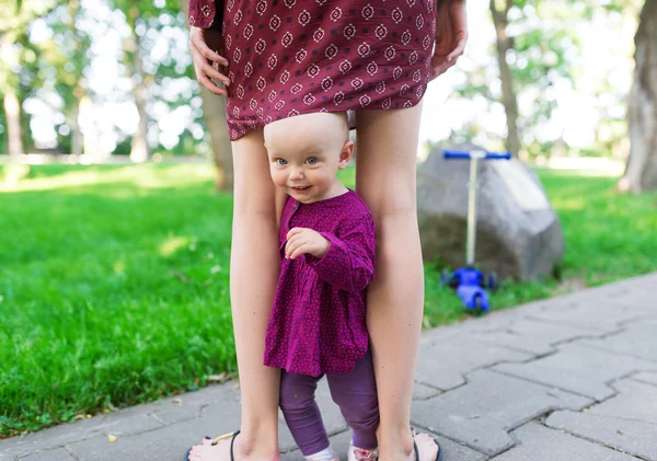 Retrato de bebé agradable sosteniendo las piernas de la madre —  Fotos de Stock