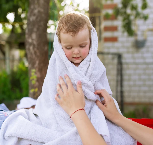 Little sad girl is wrapped up in a white towel. — Stock Photo, Image