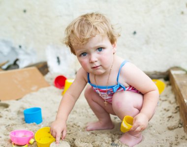 Kum havuzunda sevimli bebek çalış