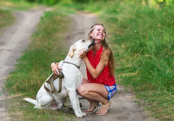 La hermosa chica y el perro se han sentado en un sendero del bosque — Foto de Stock