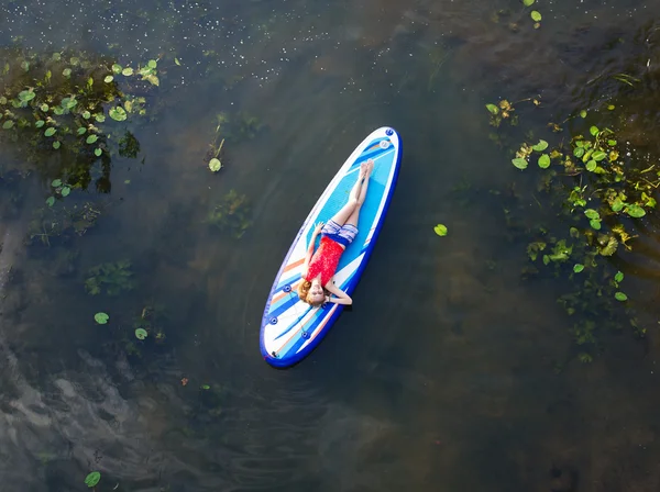 Het mooie meisje ligt op een surfplank — Stockfoto