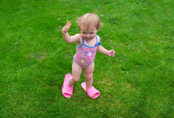 La niña en un traje de baño y step-ins corre sobre la hierba —  Fotos de Stock