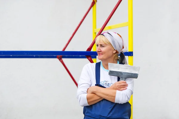 O retrato da mulher em um uniforme com a espátula nas mãos . — Fotografia de Stock