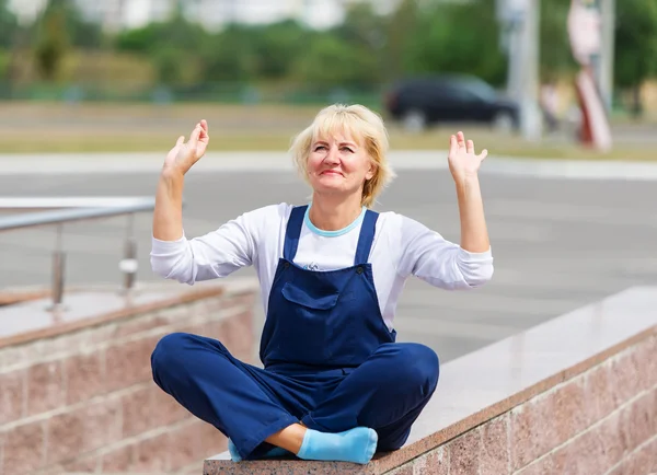 Porträtt av den glada kvinnan i uniform sitter i en lotus pose. — Stockfoto