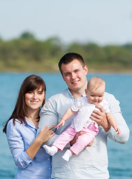 Mladá rodina poblíž jezera venkovní na podzimní den — Stock fotografie