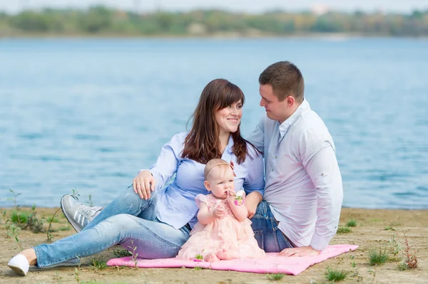 Young family near the lake outdoor on a autumn day — Stock Photo, Image