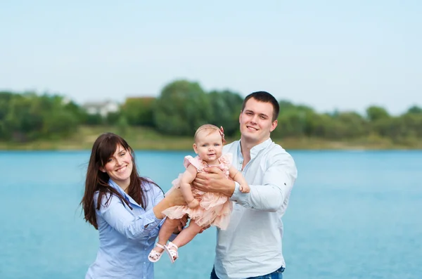 Young family near the lake outdoor on a autumn day — Stock Photo, Image