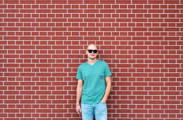Pria botak berkacamata hitam dengan latar belakang dinding bata merah — Stok Foto