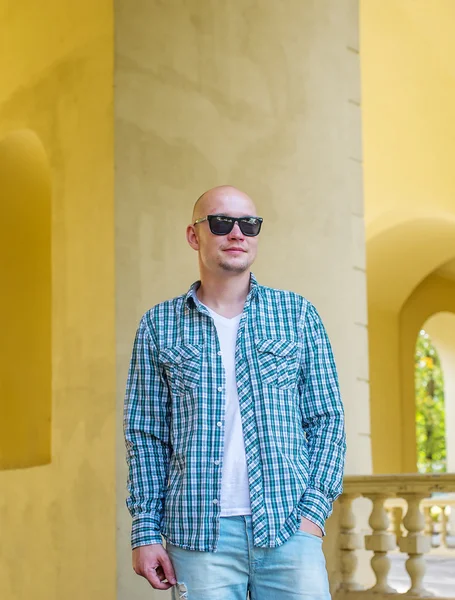 Der glatzköpfige Mann mit Sonnenbrille in Hemd und Jeans. — Stockfoto