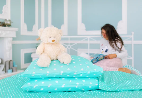 Der Spielzeug-Teddybär und die junge sexy Frau im weißen Hemd liegen im Bett — Stockfoto