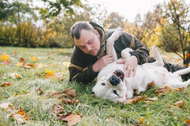 Usta köpeğiyle birlikte güneşli bir sonbahar gününün tadını çıkarıyor. Aziz Bernard köpeği. Çimlerin üzerinde birlikte oynuyorlar. Yakın çekim.