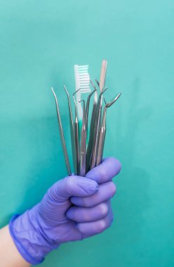 İzole edilmiş mavi arka planda diş teçhizatı ile eldivenli el.