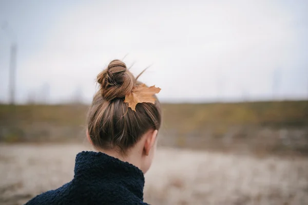 Девушка во время осеннего периода с кленовым листом в волосах — стоковое фото