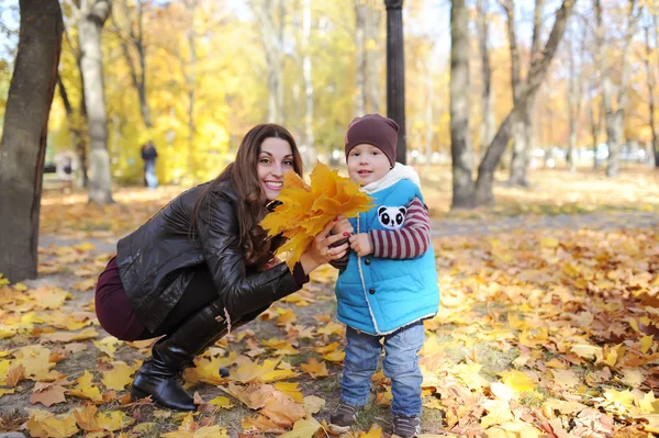 Mutter mit Sohn inmitten von Herbstlaub — Stockfoto