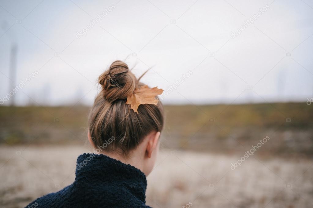 the girl during the autumn period with a maple leaf in hair