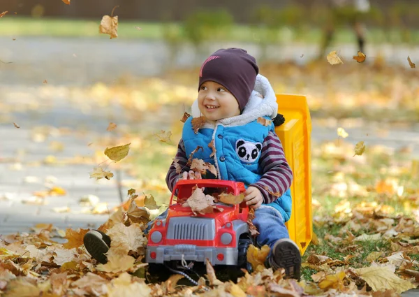 El niño juega con una máquina de juguete en el parque de otoño — Foto de Stock