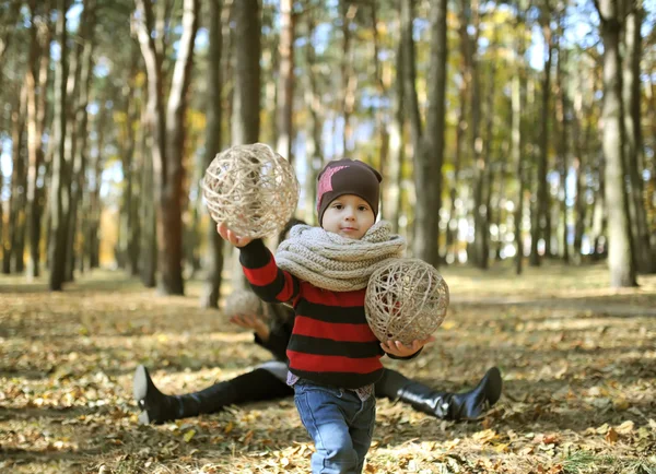 The charming kid plays among autumn gold foliage — Stock Photo, Image