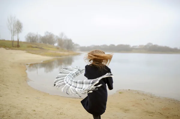 La chica con un abrigo azul camina por el río — Foto de Stock