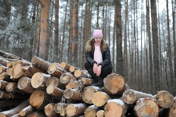 A mulher jovem posa contra logs — Fotografia de Stock